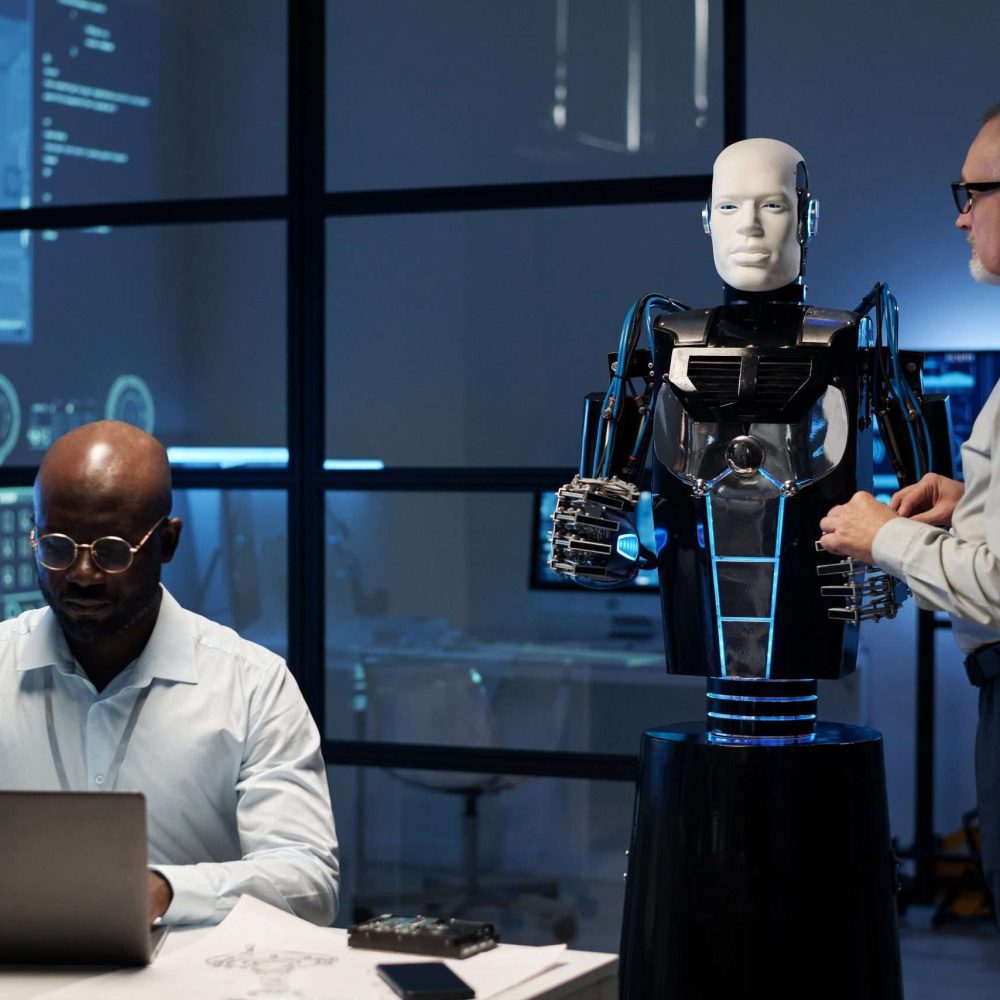 Two multiethnic engineers programming robot in the lab using computers